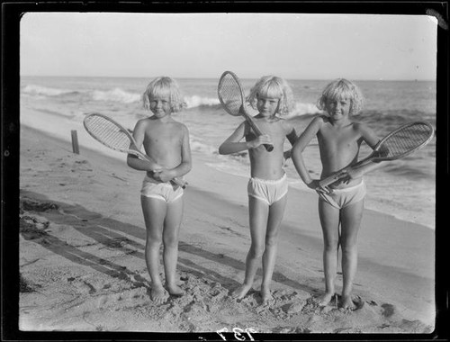 Mawby triplets with tennis rackets on beach, Malibu, 1928