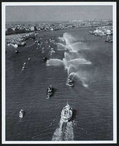 Boats in the Long Beach harbor, three fire boats spraying hoses