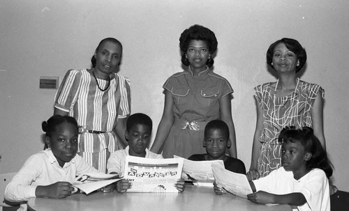 Three women posing with children holding papers, Los Angeles, 1987