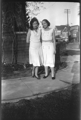 Muriel Taylor and young woman standing on walkway next to house