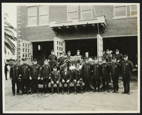 Firefighters and officials pose outside Station No. 1 with fire engine