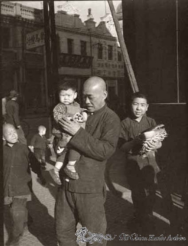 Proud father showing his child to neighbors on the streets of Tientsin, spring 1946