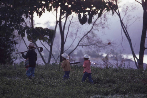 Guatemalan man and children walk near a refugee camp, Ixcán, ca. 1983