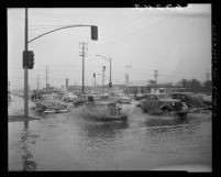 Automobiles driving through flooded intersection of Sepulveda Blvd. and Slauson Ave in Los Angeles, Calif., 1950