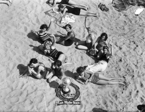 "52 Club" members lounging on the beach, view 1