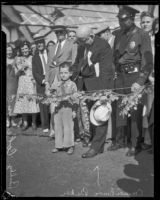 Councilman Baker and a police officer stand beside Milton "Buddy" Coleman as he cuts the ribbon to dedicate the Sixth Street Viaduct, Los Angeles, 1933
