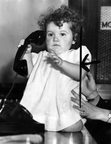 Little girl plays with a telephone