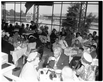 Men and women seated at dining tables with Lake Merritt in the background