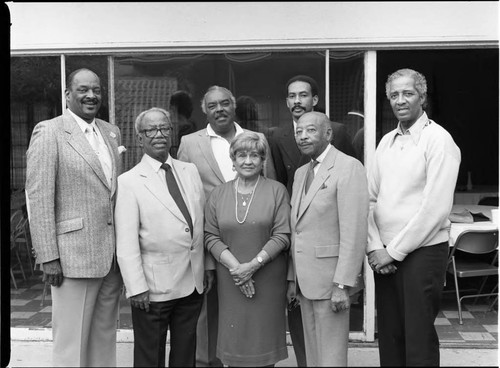 Six men and a woman posing outside of a meeting room, Los Angeles, 1985