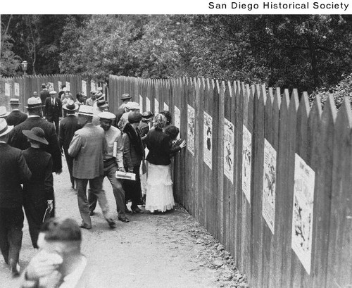People passing by the fence surrounding the nudist colony in Balboa Park during the 1935 Exposition