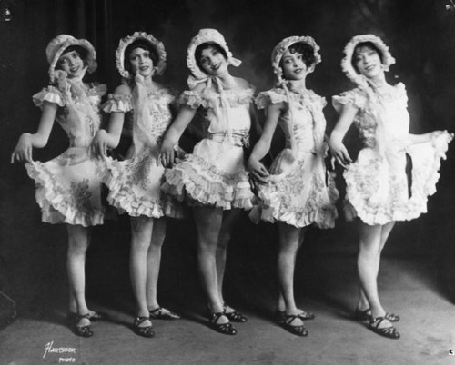 Chorus girls in ruffled dresses and bonnets