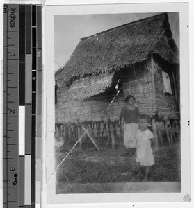 Woman and child standing in front of nipa hut, Philippines, ca. 1925
