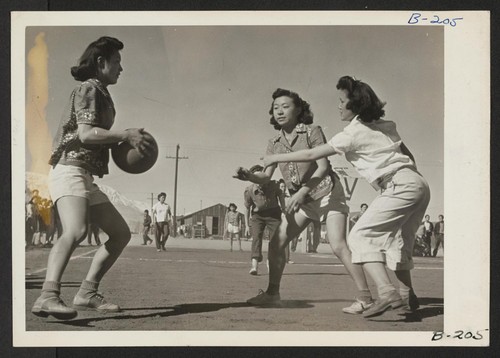Basketball games are part of the regular scheduled recreational events, which help to fill out the lives of residents in relocation centers. These girls are participating in a nip and tuck game, which frequently brought the spectators to their feet. Photographer: Stewart, Francis Manzanar, California