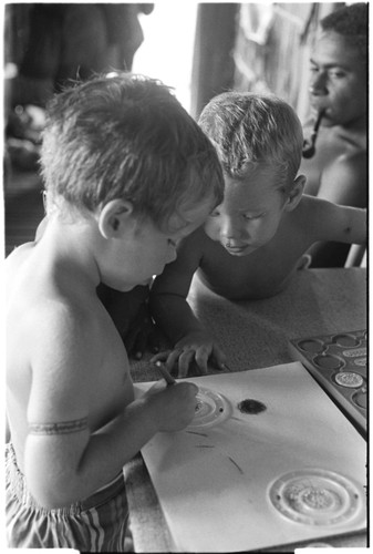 Felicia Keesing draws with a Spirograph, watched by brother, Ronald