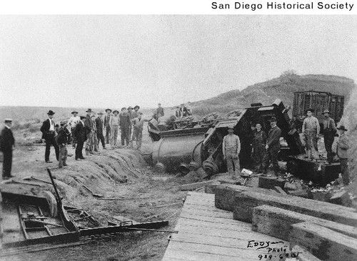 Men standing around a wrecked National City and Otay Railroad engine