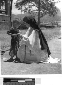 Maryknoll Sister Agnes Cazale showing a boy rosary beads, Wuchow, China, ca. 1940-1949