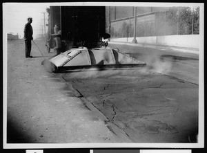 Workers using a heater to soften old surfact of asphalt on an unidentified street