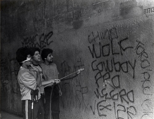 Teenage boys removing graffiti from a tunnel
