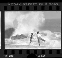 Two youngsters watching waves crash against rocks at Point Mugu State Park, Calif., 1979