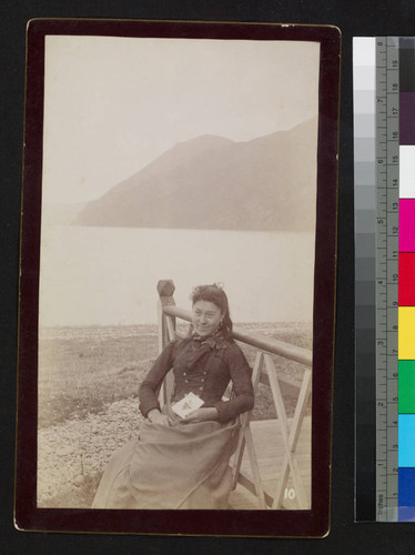 Woman, possibly native, sitting by bay with book in hand