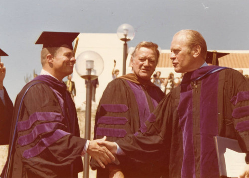 President Ford shaking hands with Fritz Huntsinger, Jr., John Wayne between them