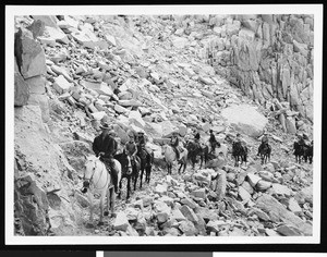 People horseback riding in a rocky mountainous site, ca.1930