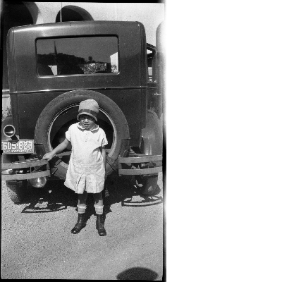 Girl standing behind automobile