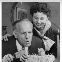 Goodwin Knight, Governor of California from 1953-1959, blows out the candles on his birthday cake as his wife Virginia looks on