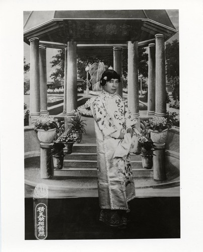 Standing actor in the role of a hua dan with painted pergola background /