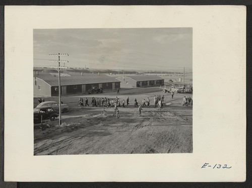 One of the last group of arrivals at the relocation center cross the warehouse area from the railroad platform to the registration office. Photographer: Parker, Tom Heart Mountain, Wyoming