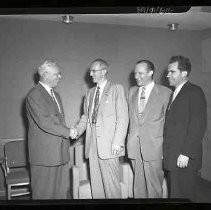 Four men, two shaking hands