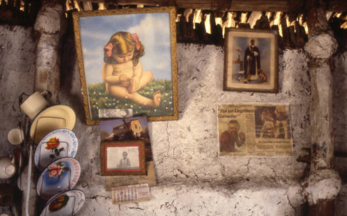 Paintings and photographs hanging from a wall, San Basilio de Palenque, 1976