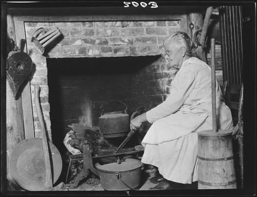 Laura Case Clark at fireplace in log cabin, San Bernardino, 1926 or 1928