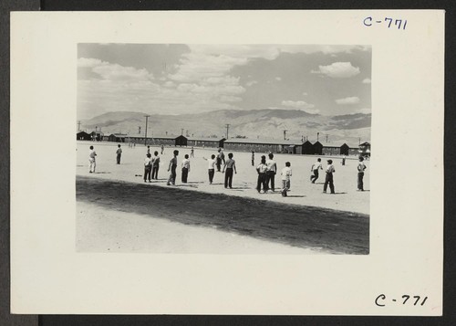 Manzanar, Calif.--Evacuees watching a baseball game at this War Relocation Authority center. This is a very popular recreation with 80 teams having been formed throughout the Center. Most of the playing is in the wide firebreak between blocks of barracks. Photographer: Lange, Dorothea Manzanar, California
