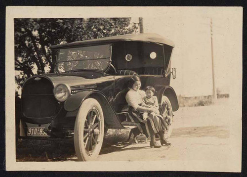 Woman and child sitting outside car
