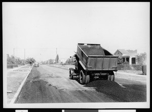 Truck dumping asphalt on an unpaved street in Los Angeles