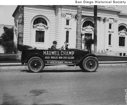 Man sitting in a 1922-23 Maxwell in front of the San Diego Carnegie Library