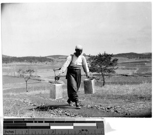 Korean man carrying water in kerosene cans, Kosai, Korea, May 1940