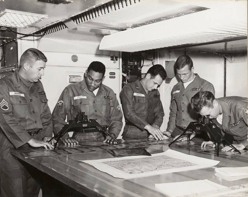 Photograph of soldiers examining maps