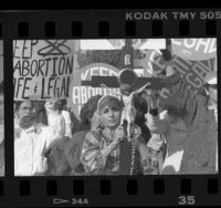 Women holding large crucifix amid protesters with "Keep Abortion Legal" signs, Los Angeles, Calif., 1989