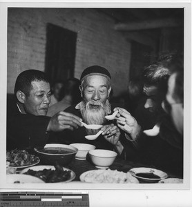 Men toasting to their meal at Wuzhou, China, 1950