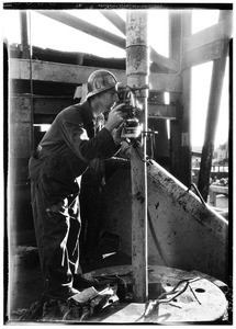 Man looking through surveying equipment inside an oil well