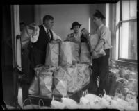Law enforcement officials George Fisher, Elizabeth Fiske, and J.W. Buckley surrounded by bags of food, Los Angeles, circa 1930