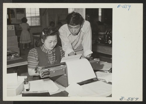 Albert Saijo, Echo editor, looks over copy being put on a mimeograph stencil by Shizu Yamaguchi, typist. Photographer: Hosokawa, Bill Heart Mountain, Wyoming