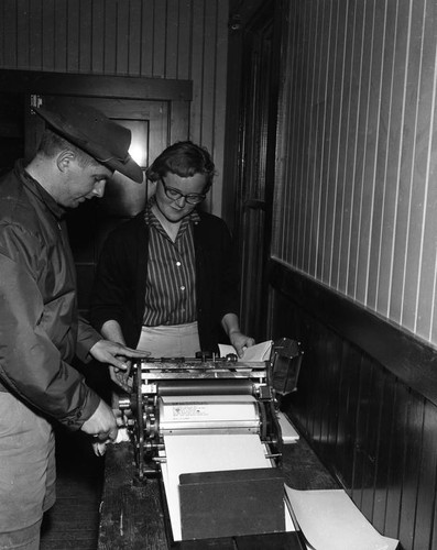 Two people using a mimeograph