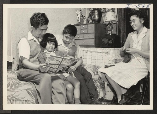 A successfully relocated Nisei family is portrayed in this picture of the Harry Taketa family. As father plays a game