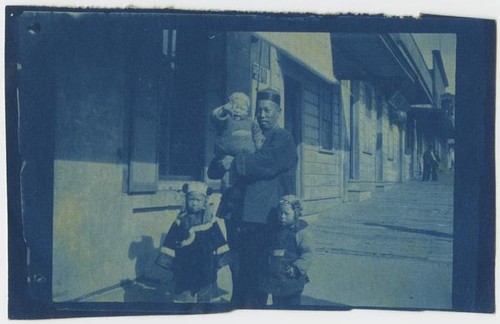 Man and Children Standing in front of Ah Louis Store
