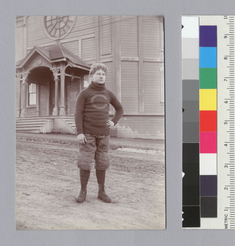 "Hopper, Jas [James], U.C. football, 1899," standing in front of Harmon Gymnasium, University of California at Berkeley. [photographic print]