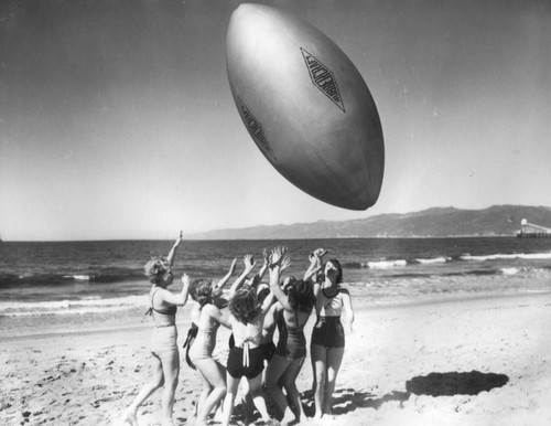 Women at the beach with giant "football", view 2