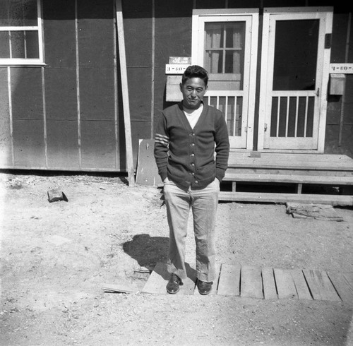 Nisei man in front of barracks in Jerome camp